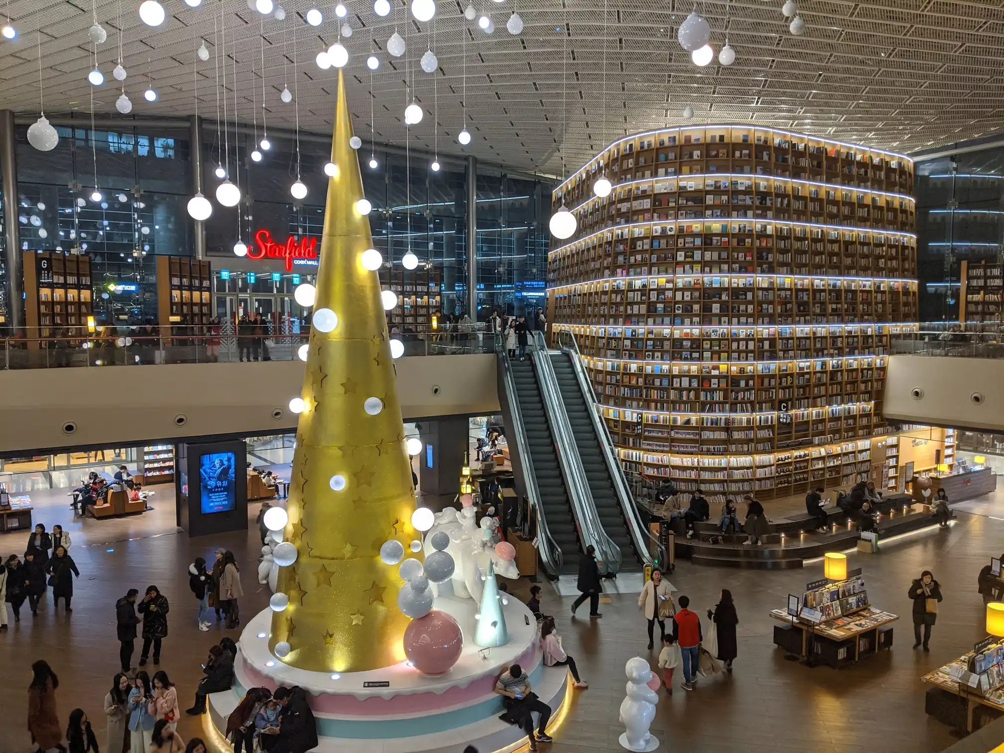 Starfield Library, Seoul — golden cake-tier Christmas tree under floating light bulbs
